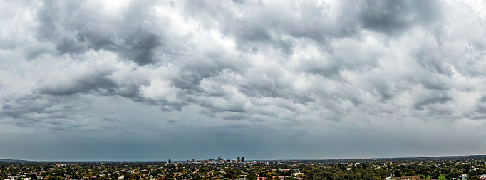 Extreme wide angle panoramic view of storm clouds gathering over the suburbs of Adelaide, South Australia with the city in the distance.