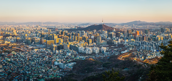 Aerial panorama over the crowded highrise cityscape of Seoul overlooked by the iconic spire of Namsan Tower in the heart of South Korea’s vibrant capital city.