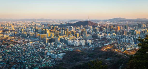 Seoul sunset panorama over crowded skyscraper cityscape South Korea Aerial panorama over the crowded highrise cityscape of Seoul overlooked by the iconic spire of Namsan Tower in the heart of South Korea’s vibrant capital city. aerial view of seoul south korea capital city stock pictures, royalty-free photos & images
