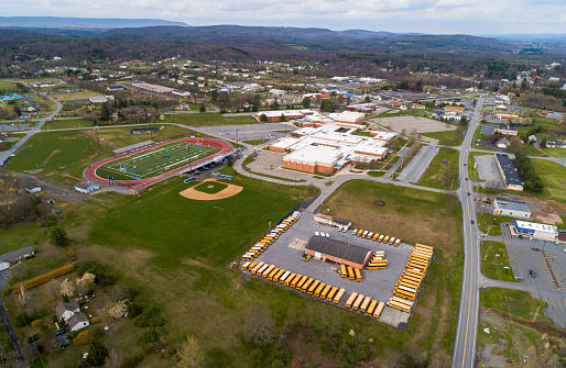 April, 25 - Brodheadsville, Pennsylvania, USA: all schools in Pennsylvania are closed until the end of the academic year because of the COVID-19 outbreak. School buses are parked permanently at the parking lot, and school buildings and the stadium are closed and deserted.