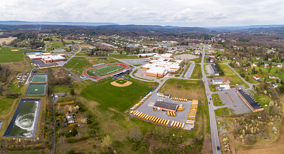 April, 25 - Brodheadsville, Pennsylvania, USA: all schools in Pennsylvania are closed until the end of the academic year because of the COVID-19 outbreak. School buses are parked permanently at the parking lot, and school buildings and the stadium are closed and deserted.