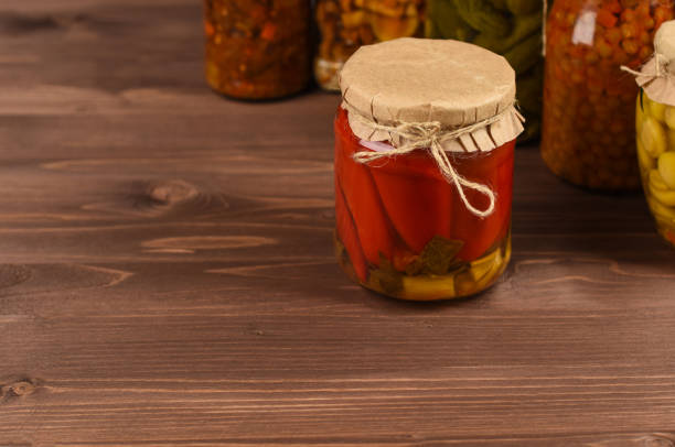 istock Canned pepper in glass jar in front of mixed marinated vegetables. 1221340997
