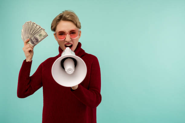 mujer joven con gafas de sol rosas con dinero gritando al altavoz - easy money audio fotografías e imágenes de stock