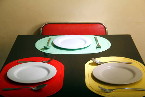 Dining table with colorful place mats, plates and utensils stock photo
