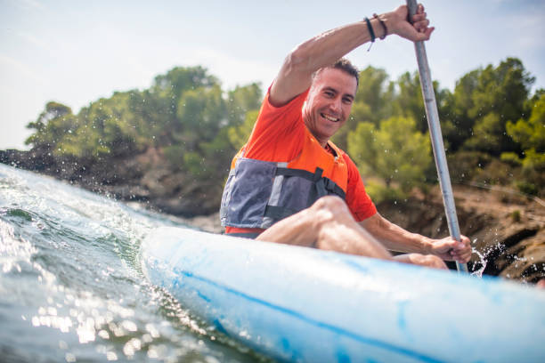 istock Smiling Fit Male Kayaker Paddling Past Camera 1221345601
