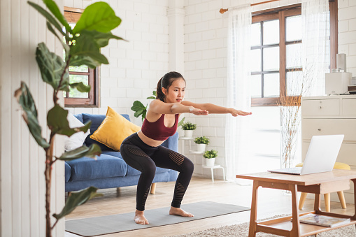 Joven asiática mujer sana entrenamiento en casa, ejercicio, ajuste, hacer yoga, concepto de fitness en el hogar photo
