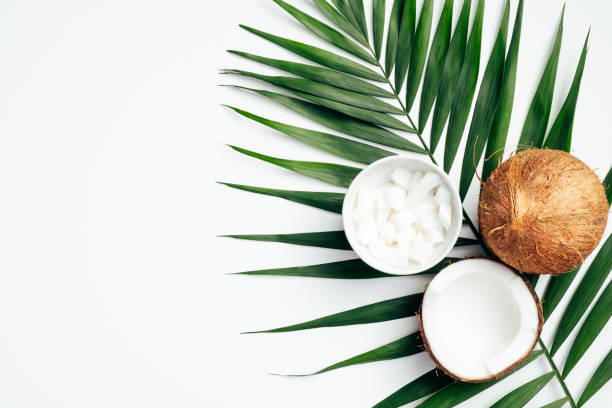 istock Coconut fruit with half and coconut flakes grated in bowl, tropical palm leaf on white background. Flat lay, top view. Summer background. 1221346078