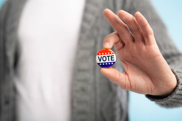 istock Man with vote pin in hand on blurred background 1221346552