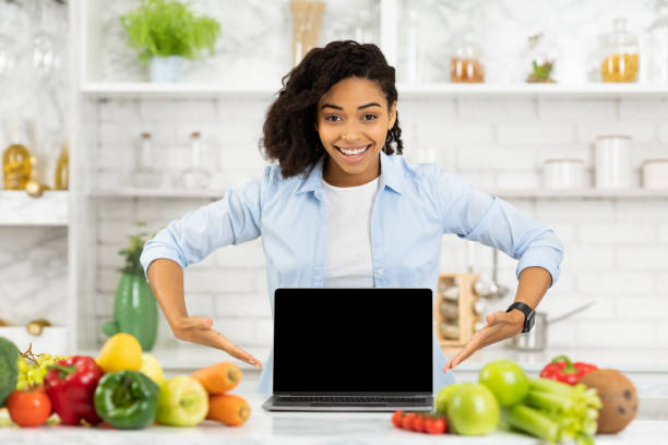 istock Afro girl pointing at laptop in the kitchen 1221347786