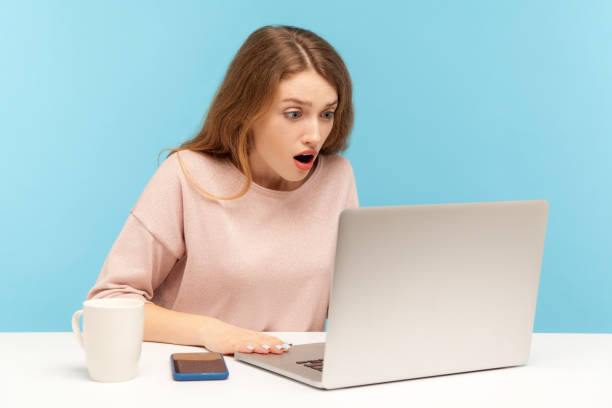 istock Wow, unbelievable! Young woman with shocked expression looking at laptop screen with open mouth, talking on video call 1221348287