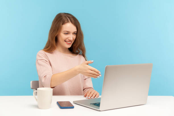 online consulting. happy businesswoman welcoming client with handshake and looking at laptop screen - gesturing interview business sitting imagens e fotografias de stock