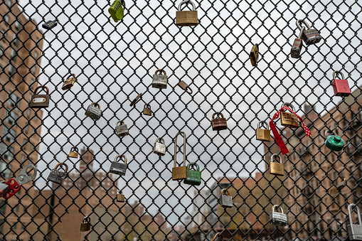 New York, NY, USA - April 23, 2020: Love locks attached to a chain link fence above train tracks on East 97th Street and Park Avenue. View north to Harlem.