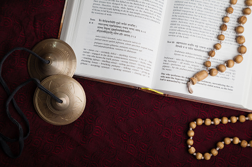 Open scripture in Sanskrit with chanting beads