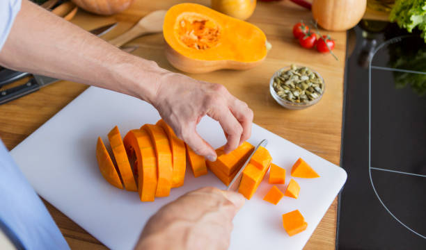 istock Man cutting fresh raw pumpkin for preparing vegan soup 1221351338