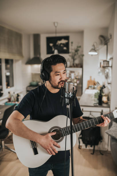 istock Japanese man practices guitar playing at home 1221351562