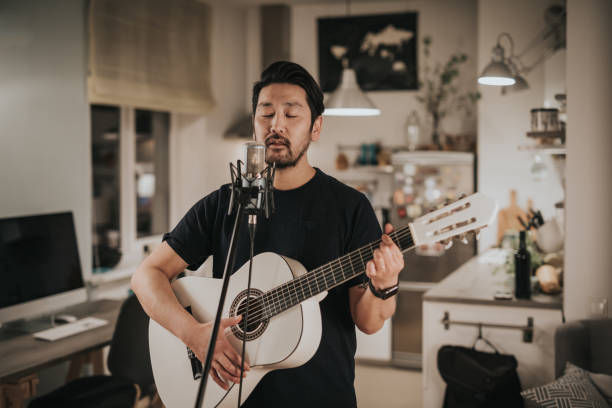 istock Japanese man sings and plays guitar at home 1221351577