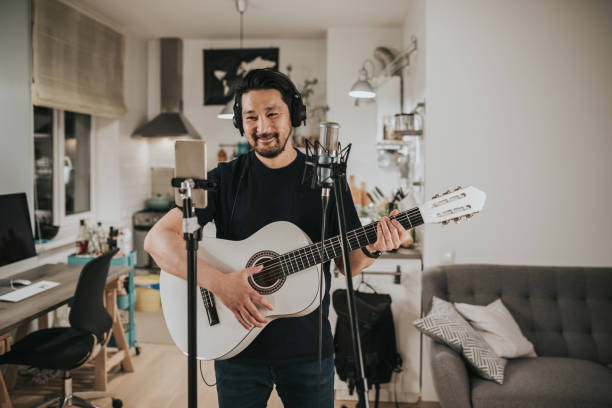 istock Japanese man communicates through video call while playing guitar with friends 1221351633