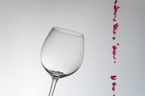 Splash of red wine in a glass, close-up on a white background