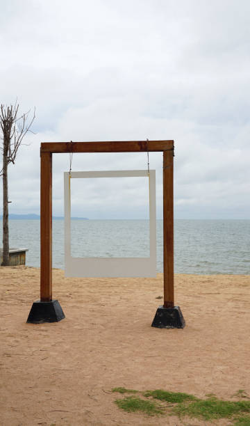istock White picture frame hanging on the timber pole with sea background 1221359007