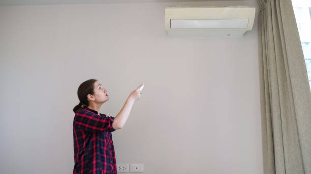 istock brunette turns on conditioner with remote control and smiles 1221360021