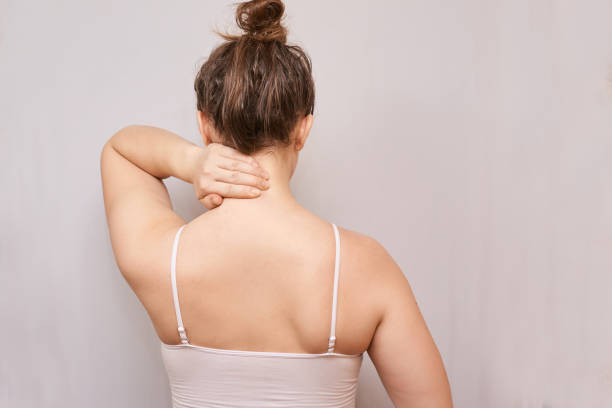 la ragazza tiene la mano vicino al collo. visualizzazione posteriore - chiropractor human spine office physical injury foto e immagini stock