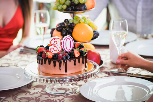 Delicioso pastel de cumpleaños con velas 30.. Concepto de vacaciones. Mujer mano con champán photo