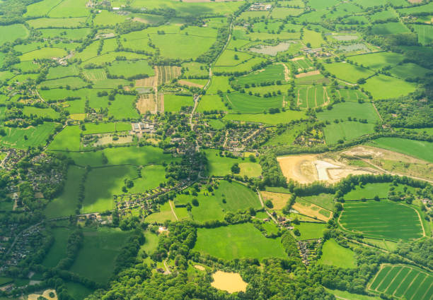Traditional English village countryside from the air An aerial summer view of patchwork fields separated by hedges and trees, with roads connecting hamlets and villages in typical English countryside. patchwork landscape stock pictures, royalty-free photos & images