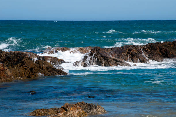 вид с пляжа горизонта и волны, разбиваемые над скалистыми обнажениями - tomakin стоковые фото и изображения