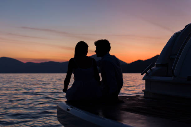 junges paar sitzt auf stern der yacht bei erstaunlichem sonnenuntergang - teenage couple stock-fotos und bilder