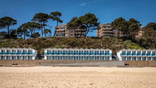 Beach huts on the coast in Dorset Beach huts on the coast in Dorset, with blocks of apartments on the cliffs poole harbour stock pictures, royalty-free photos & images