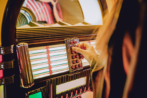 woman hand pushing buttons to play song on old Jukebox, selecting records