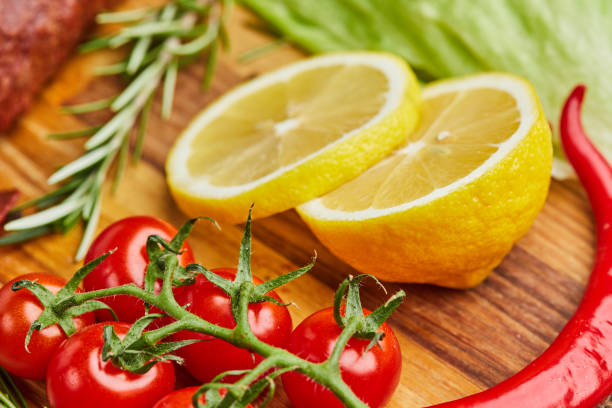 Fresh ripe tomatoes on a cutting board with rosemary, peper and lemon
