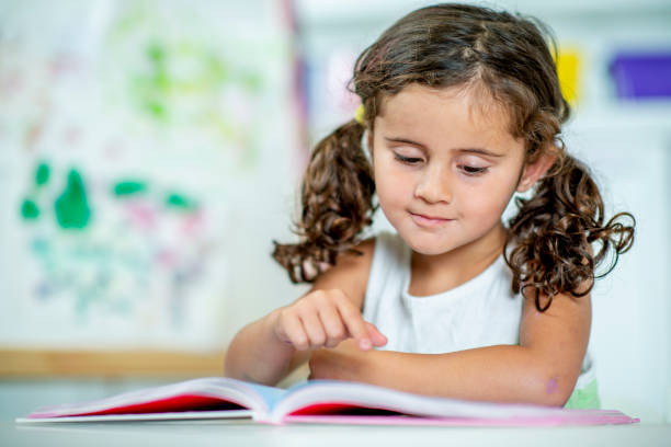 istock Cute little girl learning to read at home. 1221372640