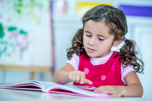 istock Cute little girl learning to read at home. 1221372649