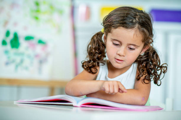istock Cute little girl learning to read at home. 1221372653