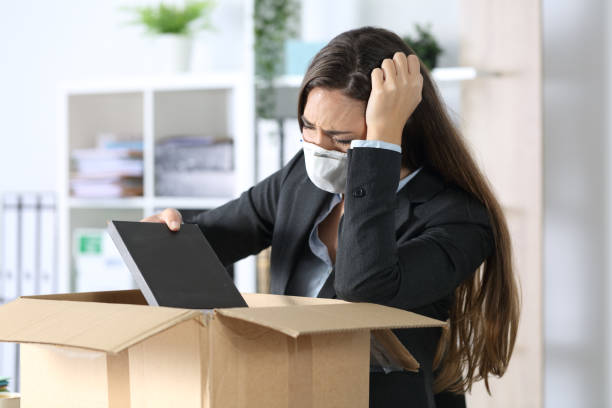 istock Fired executive with mask packing belongings at office 1221373210