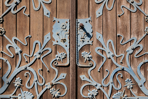 Turquoise colored metal ornaments on a brown wooden church door.