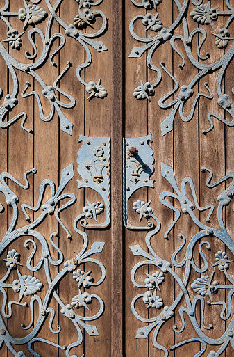 Turquoise colored metal ornaments on a brown wooden church door.