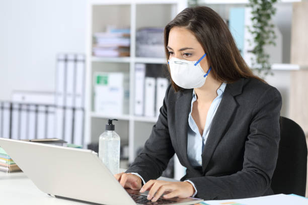 istock Executive wearing mask working on laptop at office 1221373442