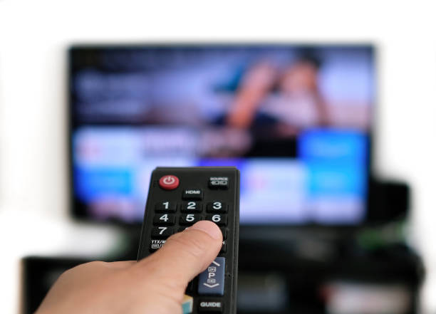 Remote control and screen - binge watching the favorite TV show stock photo