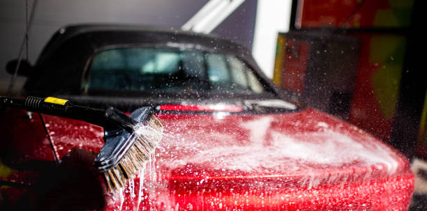 istock washing a red car convertible manually by brush with foam. 1221375130