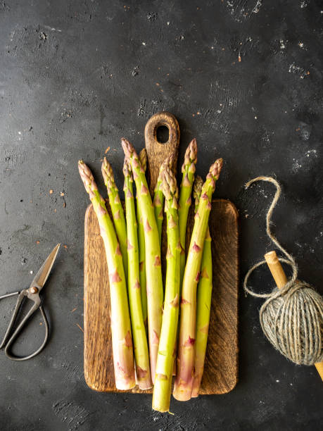 istock Fresh green asparagus on a cutting board, secateurs and yarn on a gray kitchen table 1221376846
