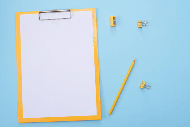 istock Yellow clipboard with blank white paper on blue background. 1221377543
