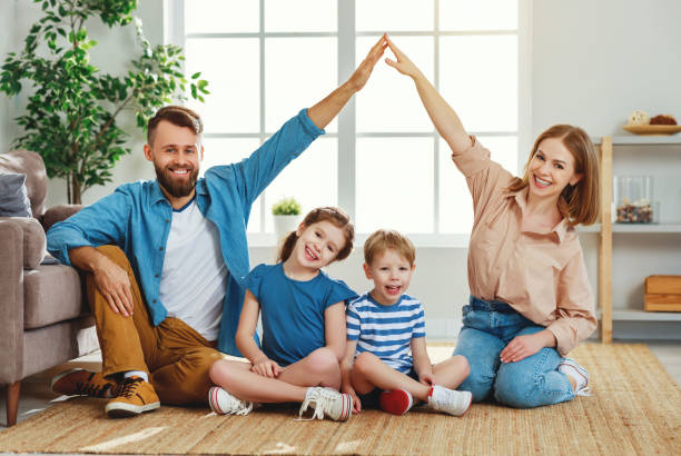 istock Happy parents making roof with hands while sitting with kids at home 1221377791