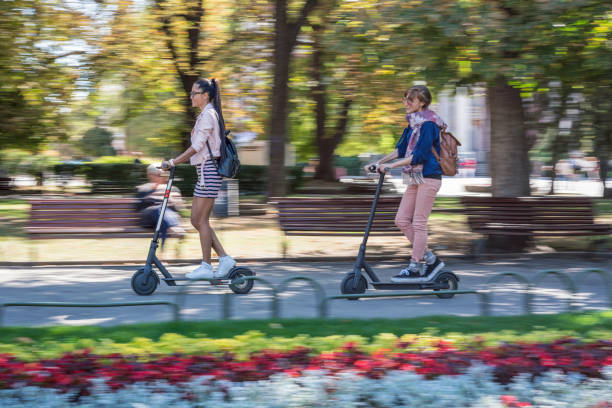 istock Girlfriends riding e-scooters through the city park 1221380419