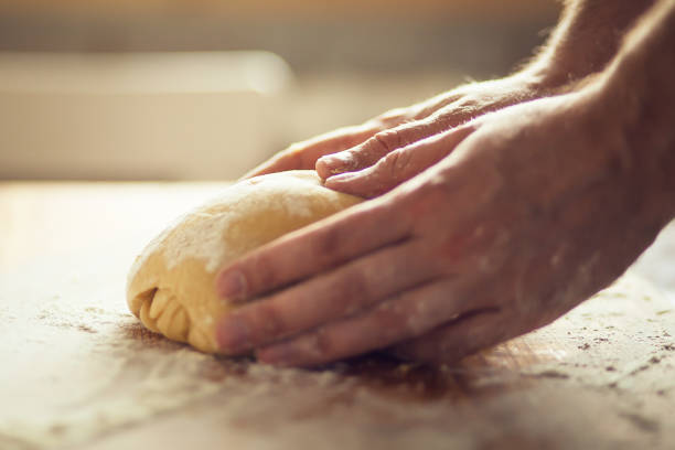 istock Man's hands kneading dough on the wooden board 1221382691