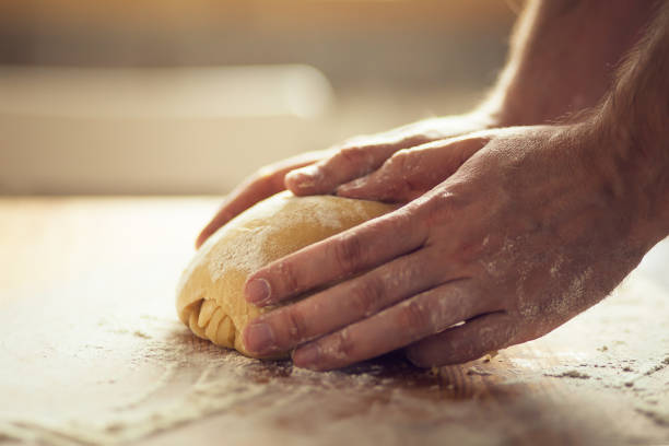istock Man's hands kneading dough on the wooden board 1221382715