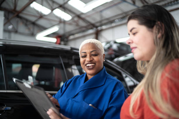 donna meccanica che parla con il suo cliente alla riparazione auto - customer auto repair shop car mechanic foto e immagini stock