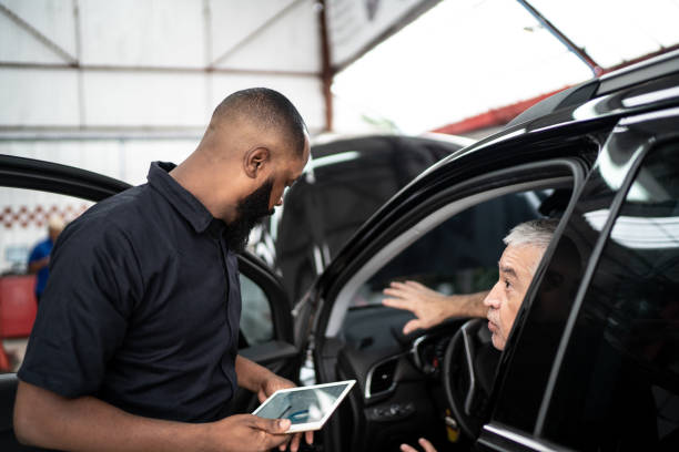 Mechanic man talking to his customer using digital tablet in auto repair Car mechanics, workers, customers, satisfaction / Auto car repair service center. auto repair shop mechanic digital tablet customer stock pictures, royalty-free photos & images