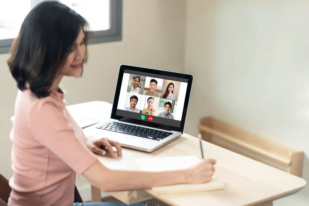 istock Asian girl using computer laptop for remote meeting conference program. Woman writing some short note after internet online discuss with office team colleague at home. Prevent for covid19 outbreak. 1221389709